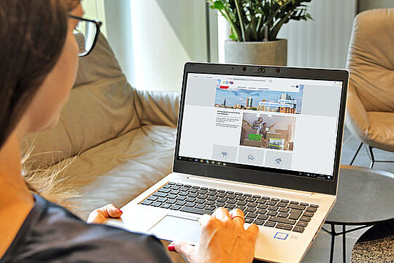 Eine Frau hat einen Laptop auf dem Schoß und schaut sich das Portal an