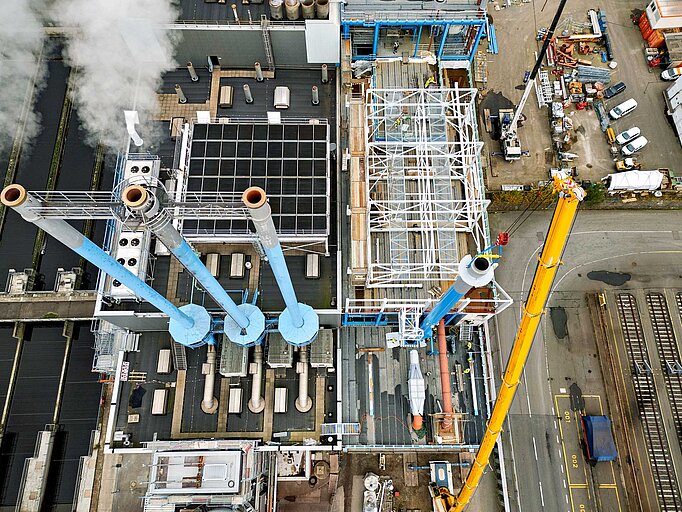 Die drei alten Kamine und der neue Kamin aus der Vogelperspektive. Neben der Baustelle sieht man auch einen Teil des Klärwerks. Klar wird: Hier ist extrem wenig Platz zum Bauen. 