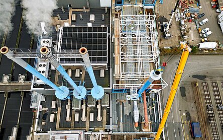 Die drei alten Kamine und der neue Kamin aus der Vogelperspektive. Neben der Baustelle sieht man auch einen Teil des Klärwerks. Klar wird: Hier ist extrem wenig Platz zum Bauen. 