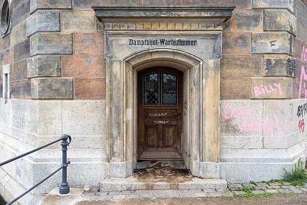Eine alte Tür im Sandstein eingelassen, über der Dampfbootwartezimmer steht