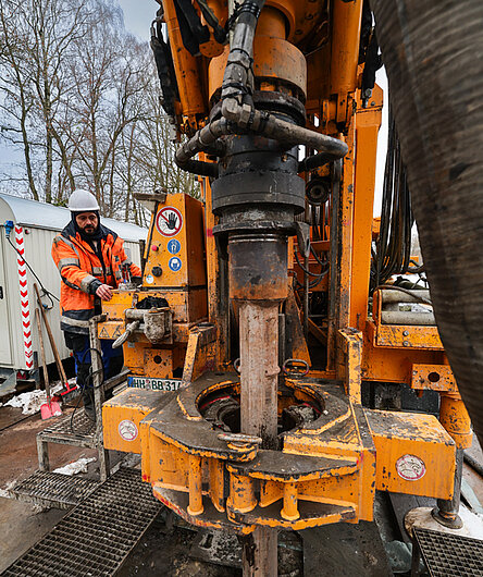 Ein Bohrfahrzeug borht mit einem Bohrkopf ein Loch in den Boden. Ein Arbeiter überwacht die Situation.