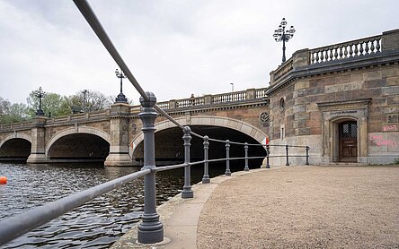 Eine alte Brücke an der Alster, in der Mauer ist ein Tor eingelassen über dem Dampfbootwartezimmer steht
