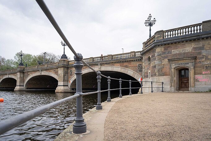 Eine alte Brücke an der Alster, in der Mauer ist ein Tor eingelassen über dem Dampfbootwartezimmer steht