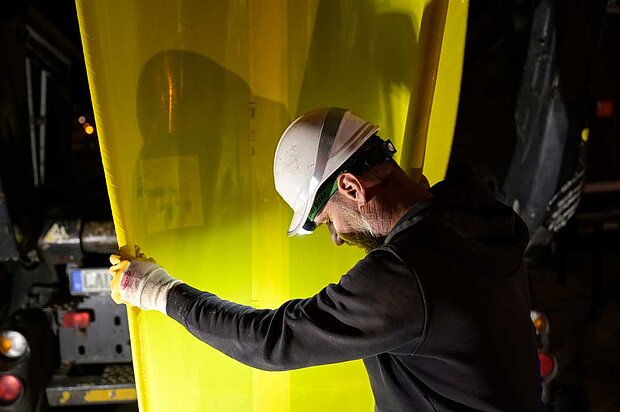 Ein Facharbeiter hält einen Schlauch, der ins Siel abgelassen wird.