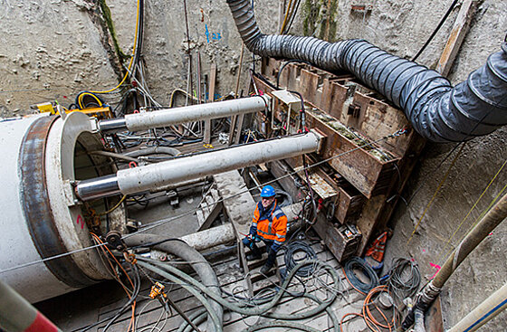 Ein Rohrelement ist mit Stützen an der Wand verkeilt und wird mit ordentlich Druck in die Baugrube gebracht. Das Foto ist aus der Vogelperspektive aufgenommen.