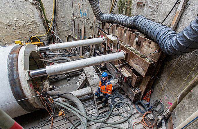 Ein Rohrelement ist mit Stützen an der Wand verkeilt und wird mit ordentlich Druck in die Baugrube gebracht. Das Foto ist aus der Vogelperspektive aufgenommen.