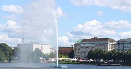 Die Alsterfontäne sprudelt vor blauem Himmel