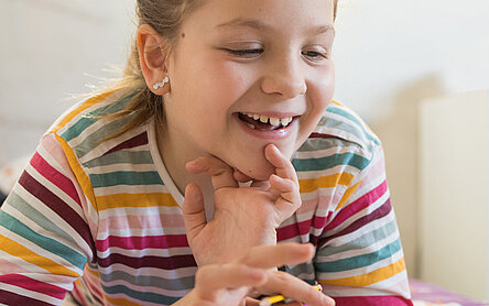 Ein Kind schaut lachend auf einen Laptop