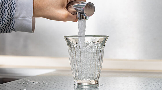 Ein Wasserhahn, aus dem frisches Trinkwasser in ein Glas läuft