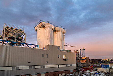 Die beiden Silos vor dem Himmel bei Sonnenaufgang fotografiert. Sie sind in weißer Folie eingepackt