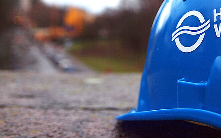 SYMBOLFOTO Blauer HAMBURG WASSER Helm vor unscharfem Hintergrund.