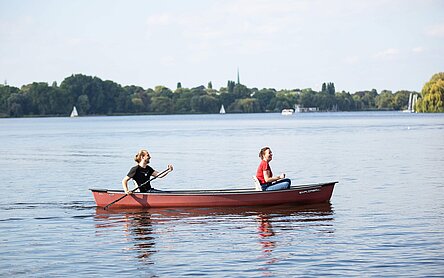 Zwei Menschen rudern in einem Ruderboot auf der Außenalster