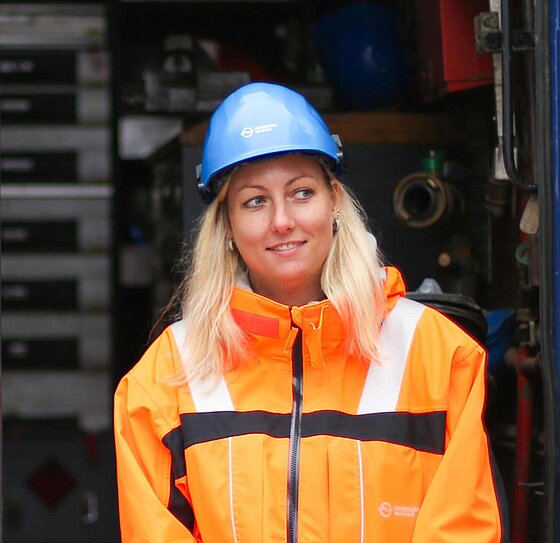 Wassermeisterin Stephanie mit Signaljacke und Helm vor HAMBURG WASSER Fahrzeug